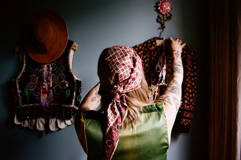 Meisje met sjaal om hoofd hangt kleren op in atelier