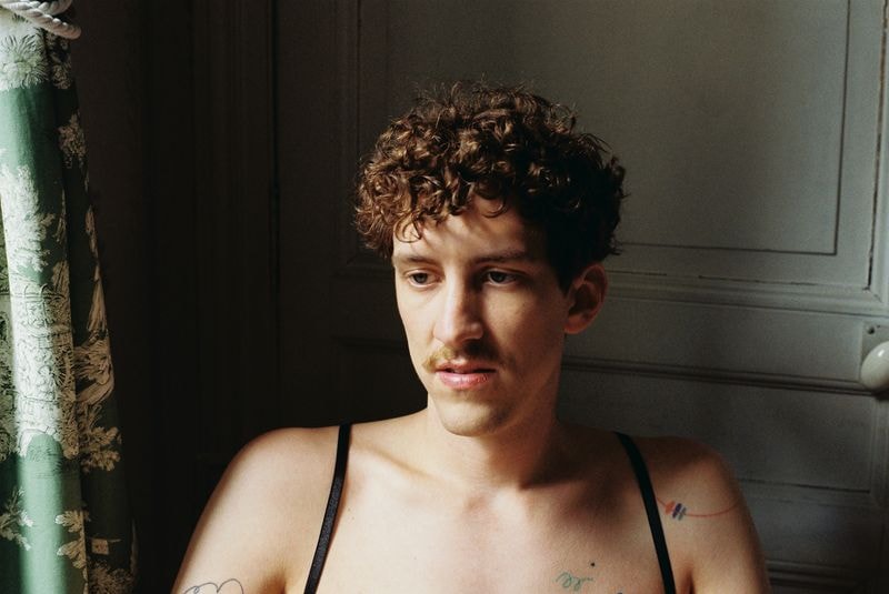 Man kijkt naar beneden, zittend naast raam met zacht licht