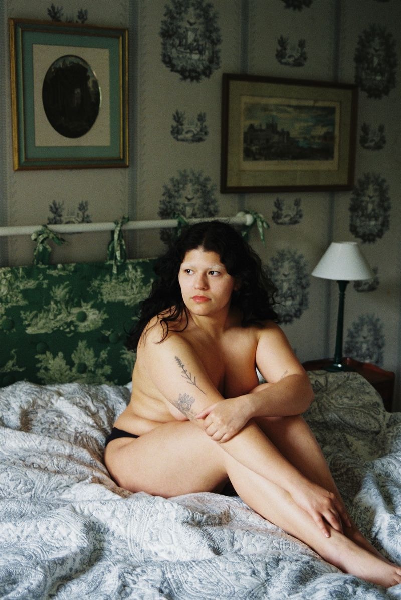 Meisje zit op bed in Frans château met sfeervol interieur, kijkt weg