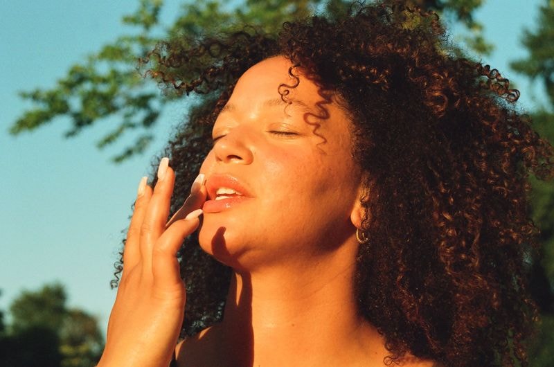 Meisje in Utrechts veld doet lippenbalsem op in de zomerzon