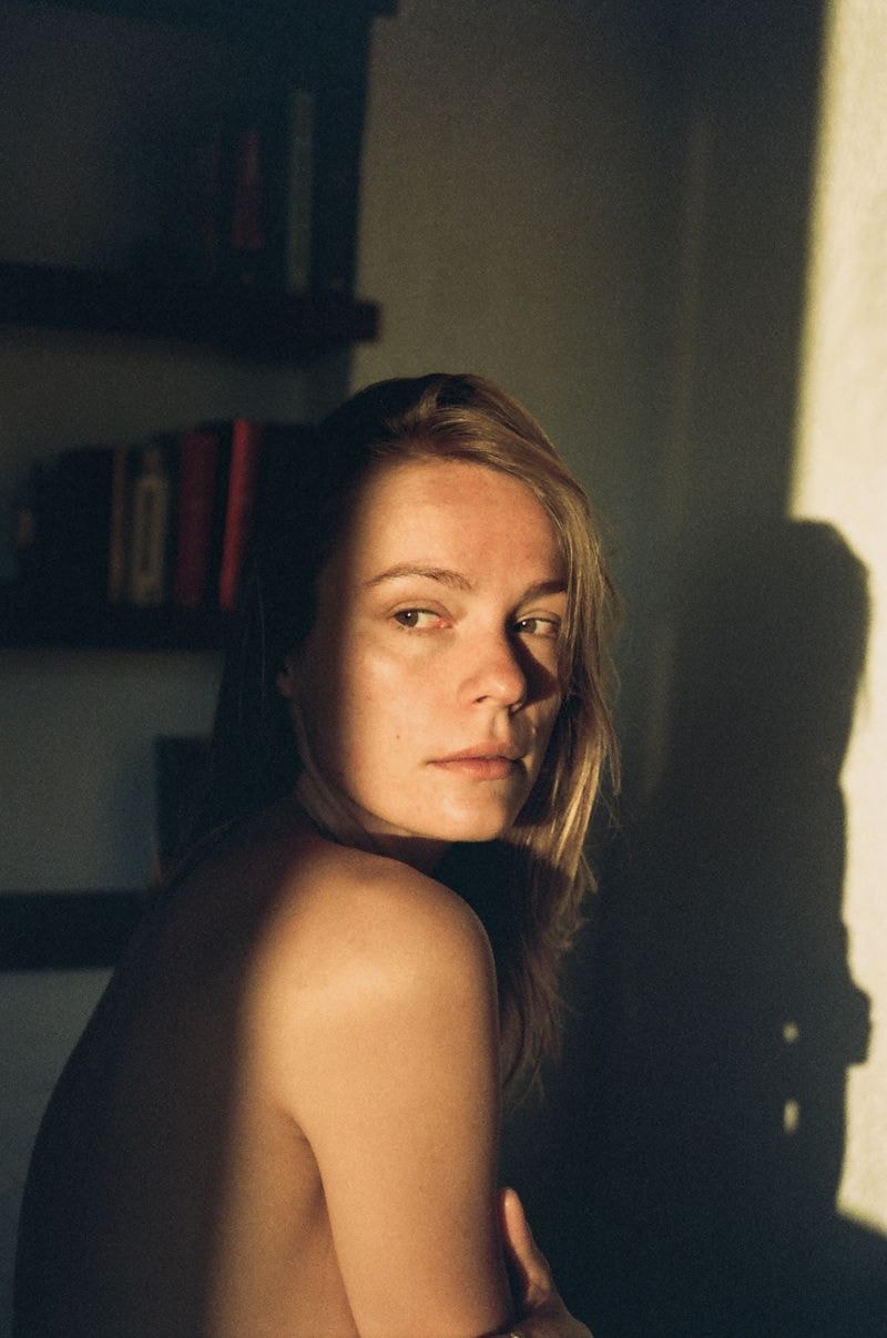 Meisje kijkt weg terwijl de zon haar gezicht op bed in Sitges in ochtendlicht verwarmt