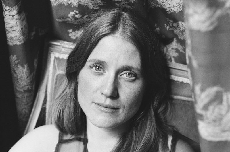 Zwart-wit portret van vrouw zittend in stoel, met scherpe blik in camera