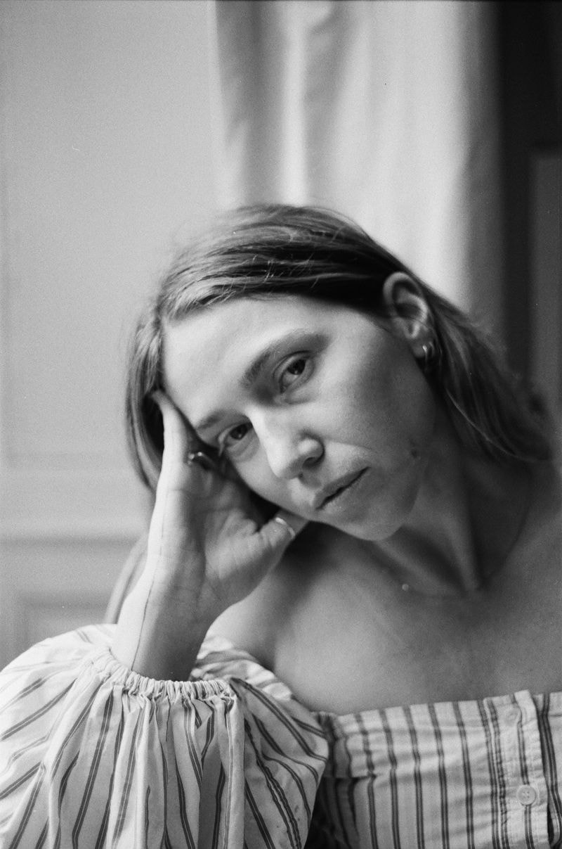 Meisje leunt met hoofd op hand in een Frans château, met een dromerige blik en zacht invallend licht