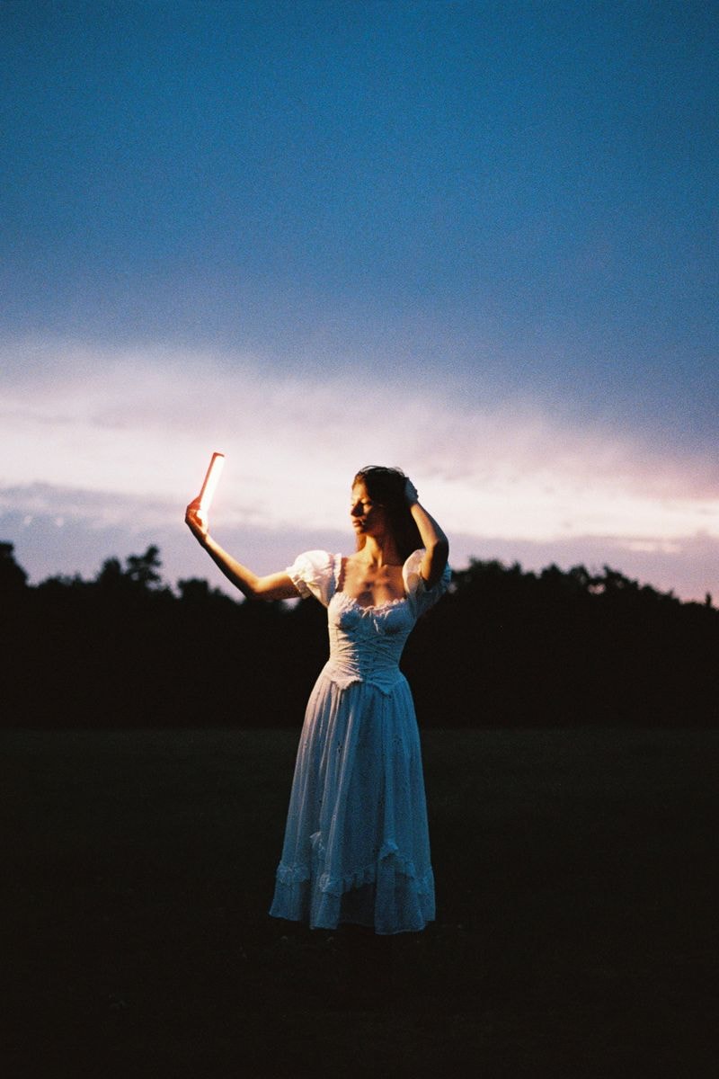 Meisje staat in veld in ochtendlicht dromerig warm portret