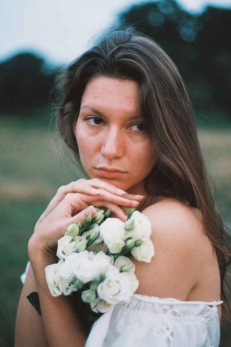 Meisje in veld met bos witte bloemen, dromerig kijkend naar de horizon in een utrechts veld