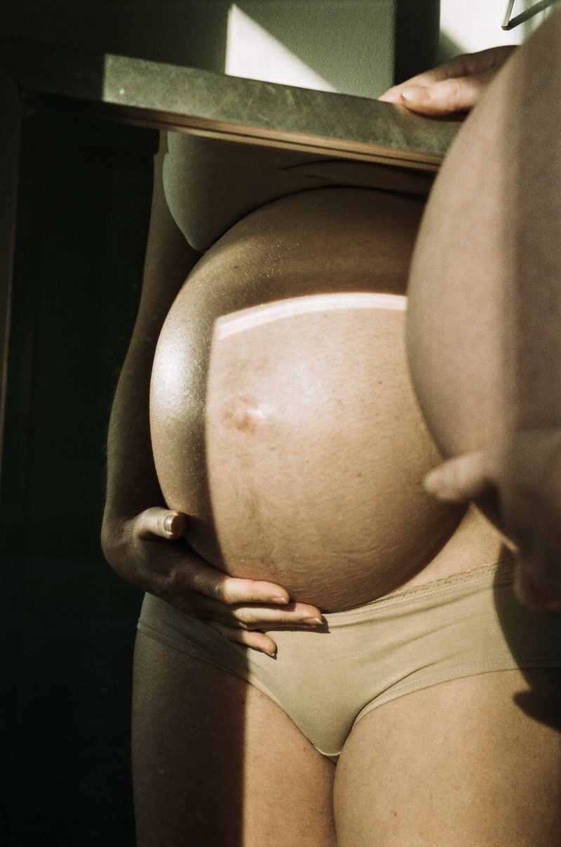 Zwangere buik reflecterend in spiegel, verlicht door zonlicht