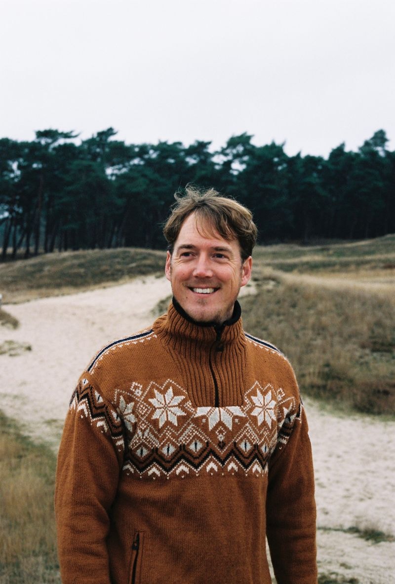 Jongen in oranje trui staand in weide in Zeist tijdens de herfst