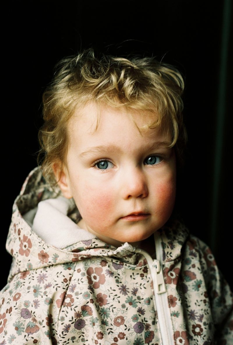 Jong meisje in bloemenjasje kijkt nostalgisch in camera in Utrecht