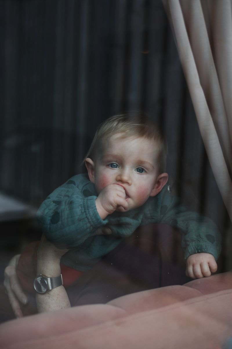 Jongen met duim in mond kijkt dromerig door raam